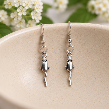 Silver-tone mouse earrings hanging in a speckled ceramic bowl