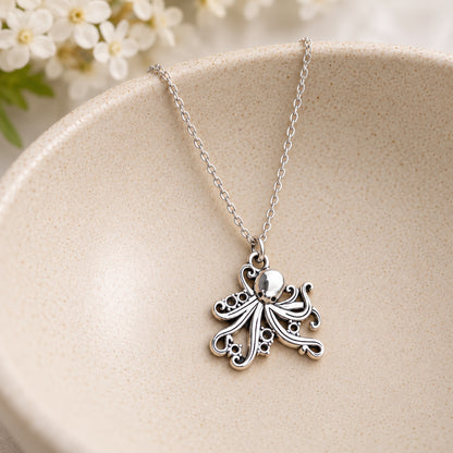 Silver-tone octopus chain necklace resting in a speckled ceramic bowl