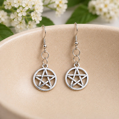 Silver pentagram circle earrings resting in a speckled ceramic bowl