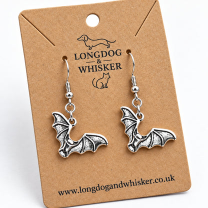 Close-up of silver-tone bat earrings showing raised wing ribs and dark recessed details