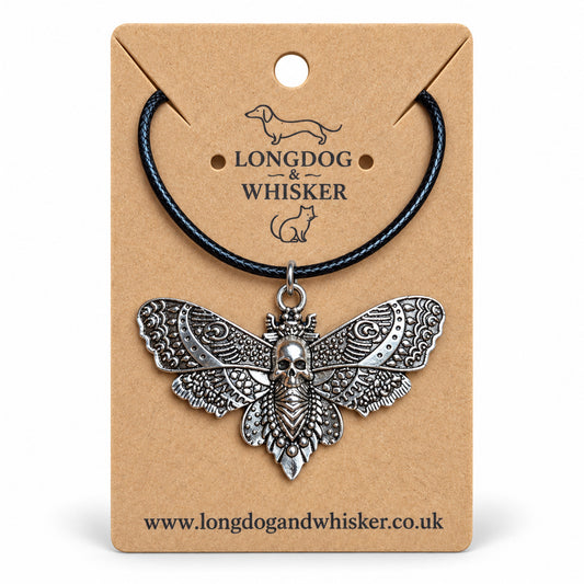 Silver skull moth necklace on black cord, displayed on a Longdog & Whisker kraft card