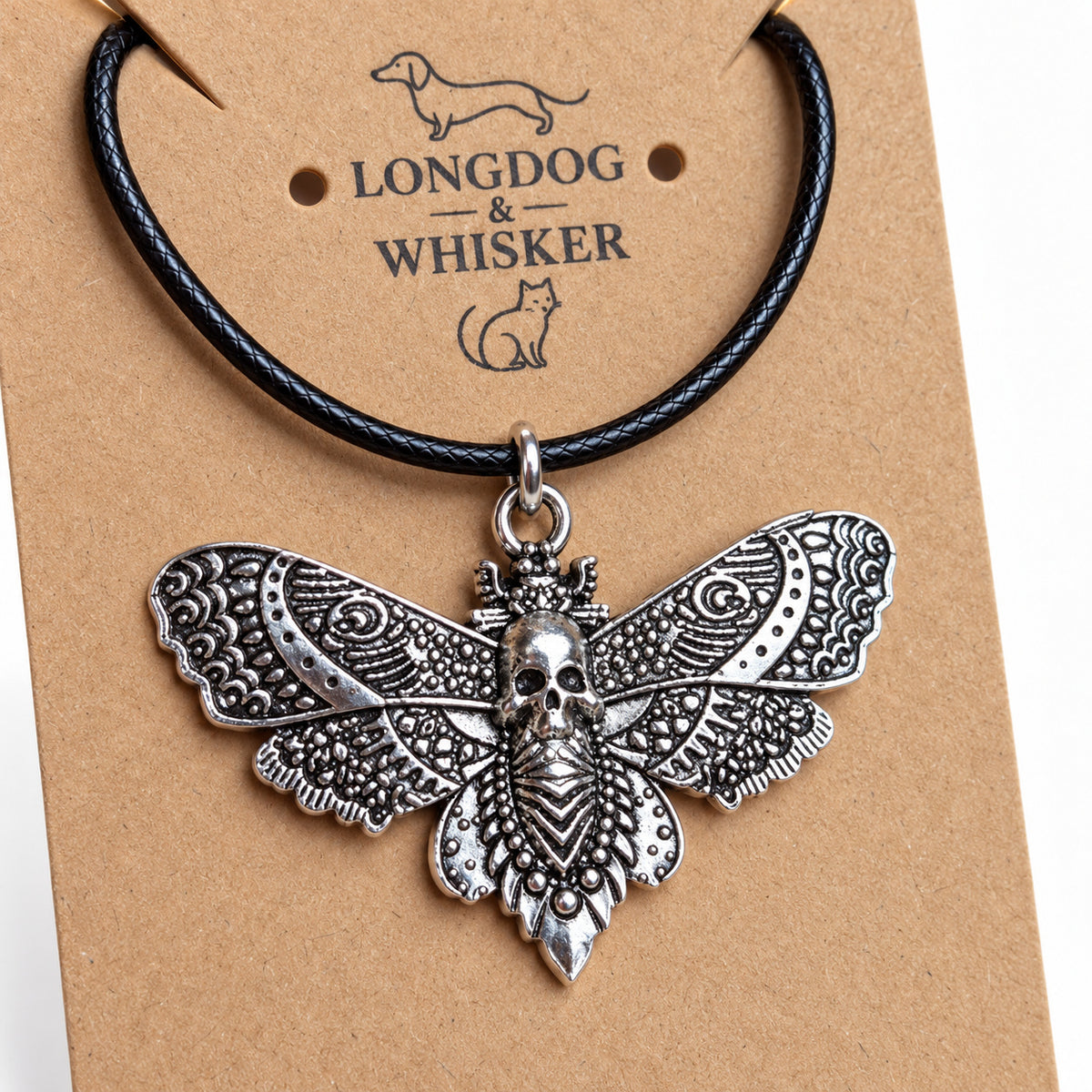 Close-up of the raised skull and ornate wings of the silver-tone moth pendant on black cord
