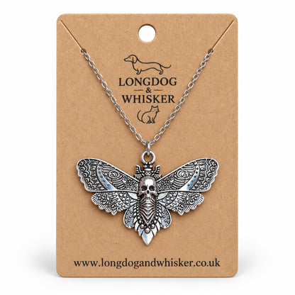 Silver-tone skull moth necklace on a silver chain, displayed on a Longdog & Whisker kraft card