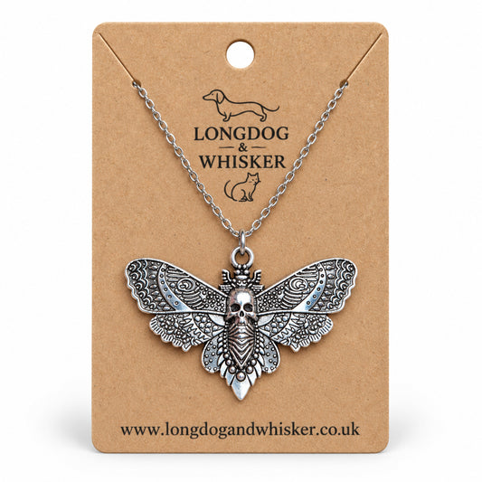 Silver-tone skull moth necklace on a silver chain, displayed on a Longdog & Whisker kraft card