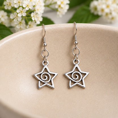Silver-tone spiral star earrings hanging in a speckled ceramic bowl
