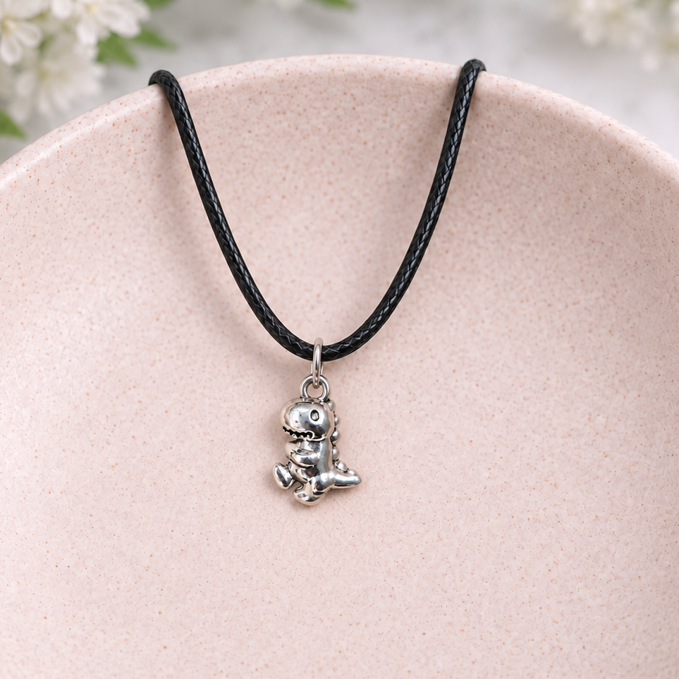 Silver T-Rex Dinosaur Necklace displayed in a pale pink bowl