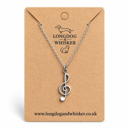 Silver-tone treble clef music note necklace on a silver-tone chain on its kraft product card