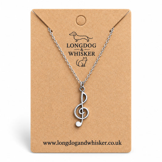 Silver-tone treble clef music note necklace on a silver-tone chain on its kraft product card