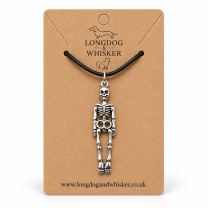 Silver-tone skeleton pendant on a black cord, displayed on a Longdog & Whisker kraft card