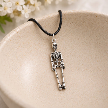 Skeleton black-cord necklace resting in a speckled ceramic bowl