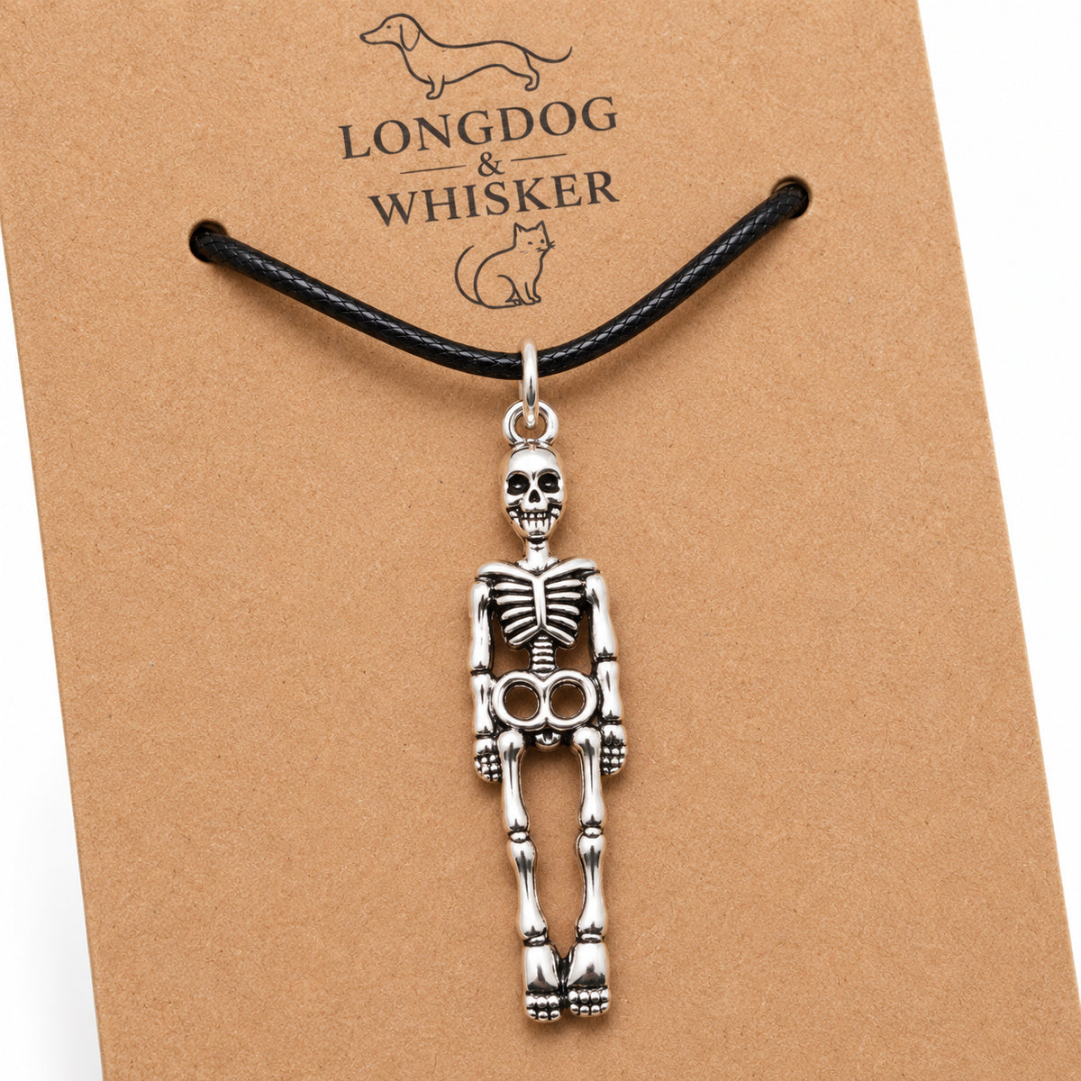 Close-up of the silver-tone skeleton pendant and black cord on kraft card