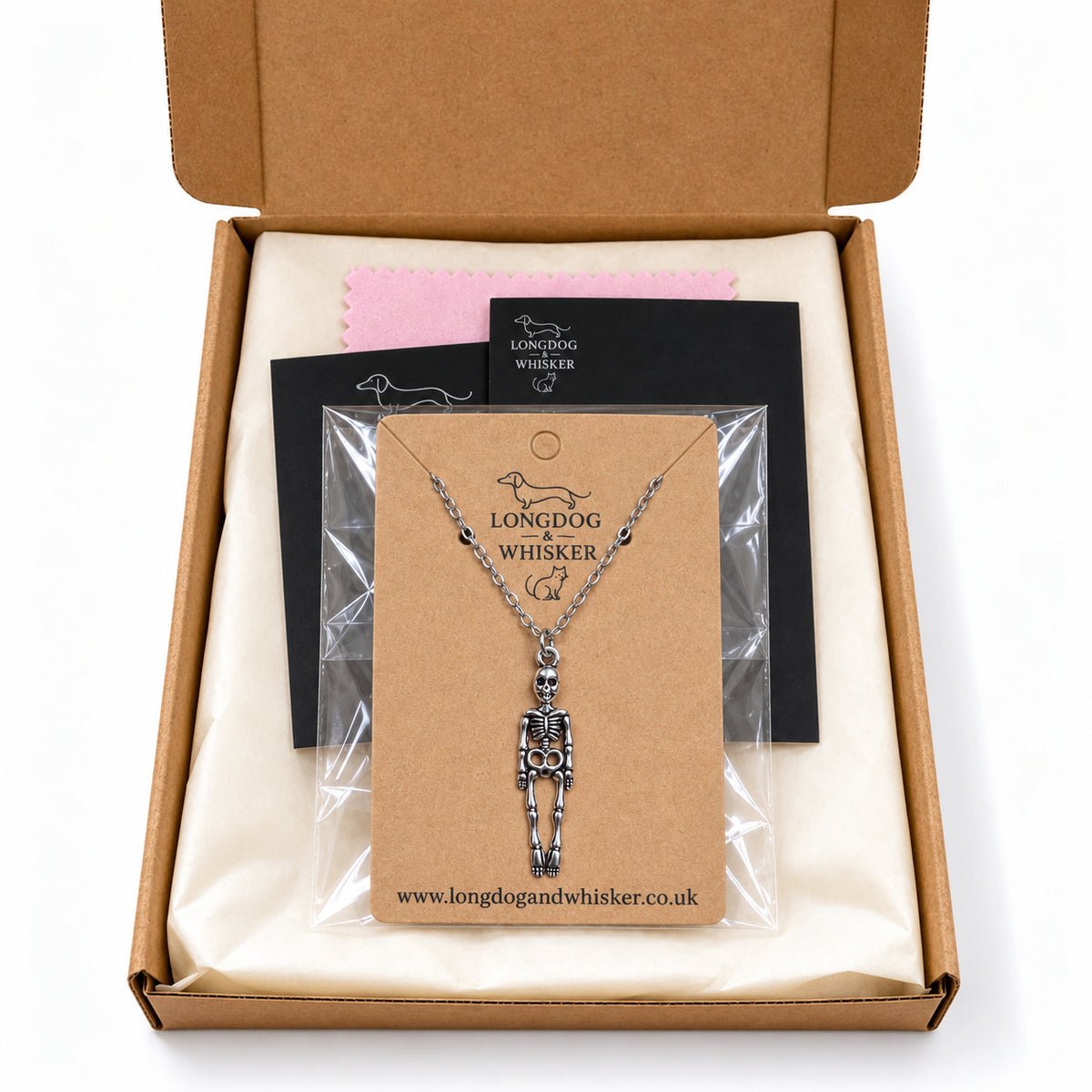 Skeleton silver-chain necklace on its kraft card inside Longdog & Whisker postal packaging