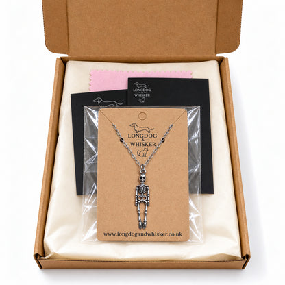 Skeleton silver-chain necklace on its kraft card inside Longdog & Whisker postal packaging