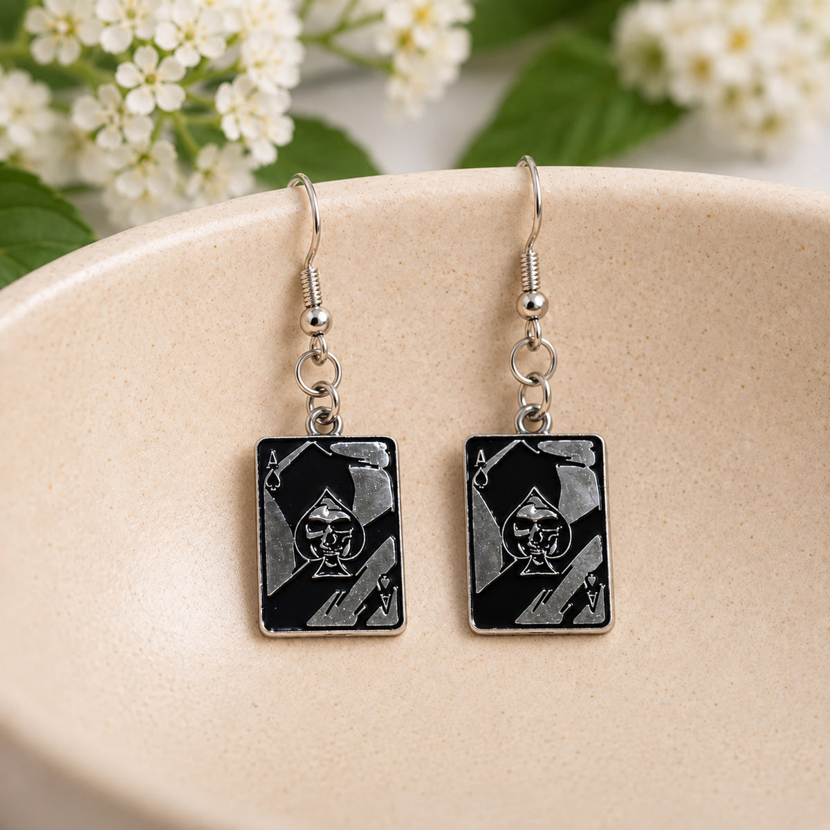 Skull Ace of Spades playing card earrings in a speckled ceramic bowl