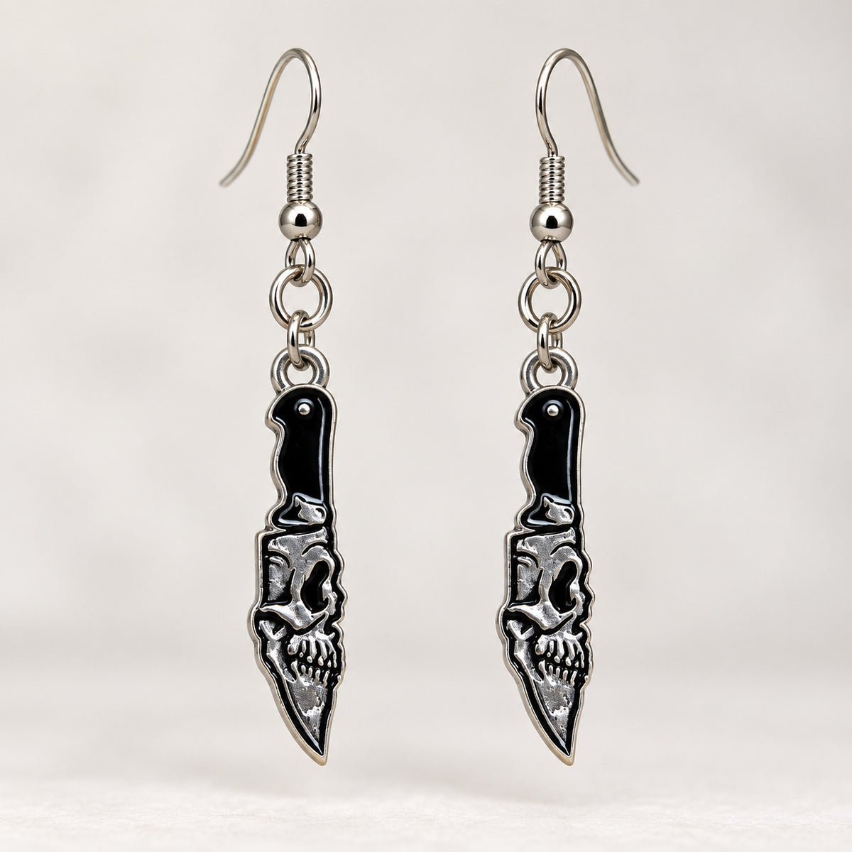 Close-up of the skull detail, black handles and pointed blades on the earrings