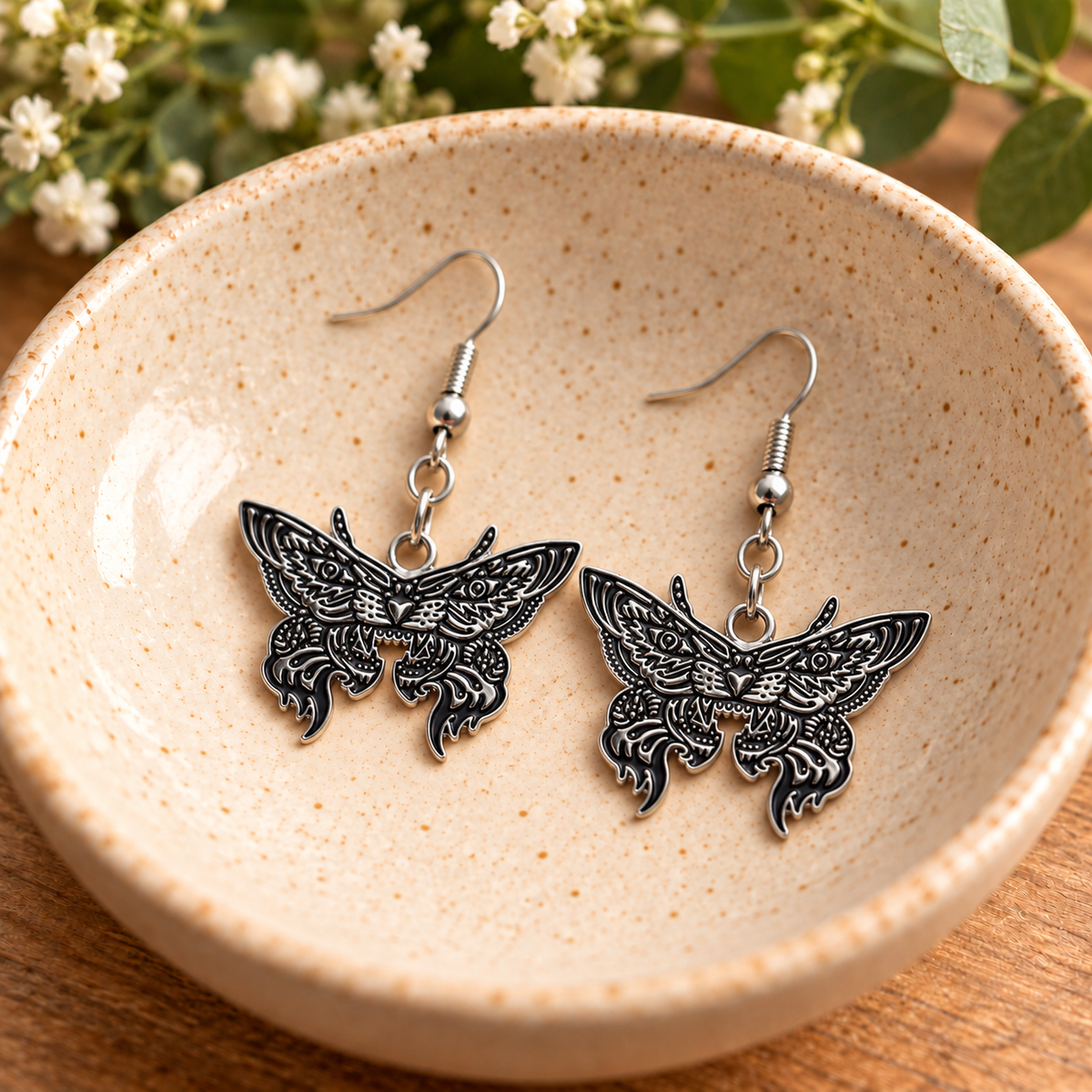 Silver Tiger Moth Drop Earrings in a speckled ceramic bowl