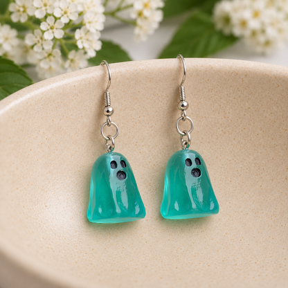 Translucent aqua ghost earrings resting in a speckled ceramic bowl.