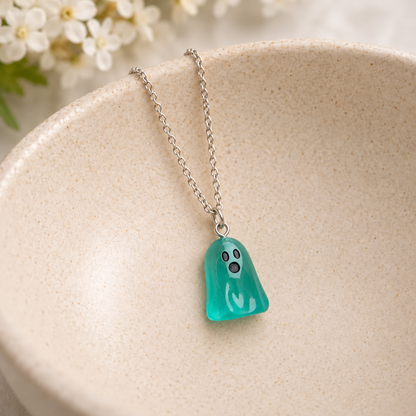 Aqua ghost necklace resting in a speckled ceramic bowl.