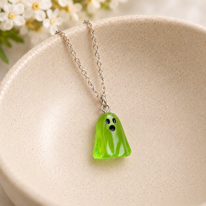 Translucent green ghost necklace resting in a speckled ceramic bowl.