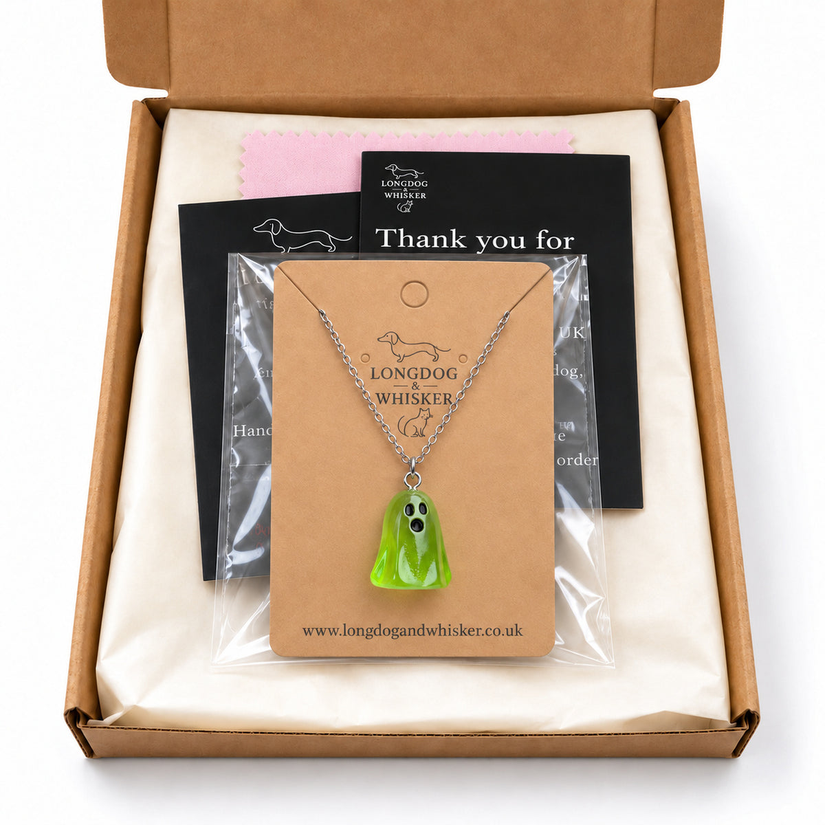 Translucent green ghost necklace on its card in Longdog & Whisker postal packaging.
