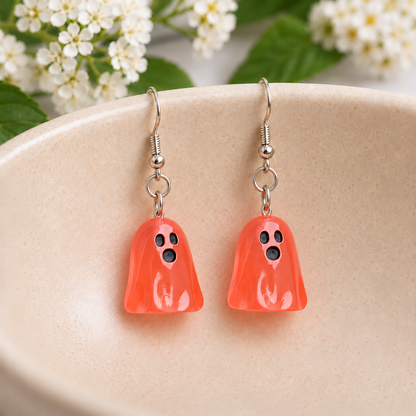 Translucent pale red ghost earrings resting in a speckled ceramic bowl