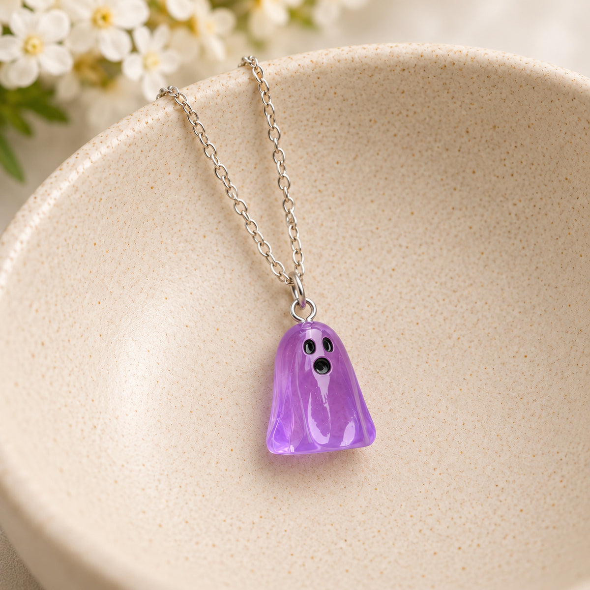 Translucent purple ghost necklace resting in a speckled ceramic bowl.