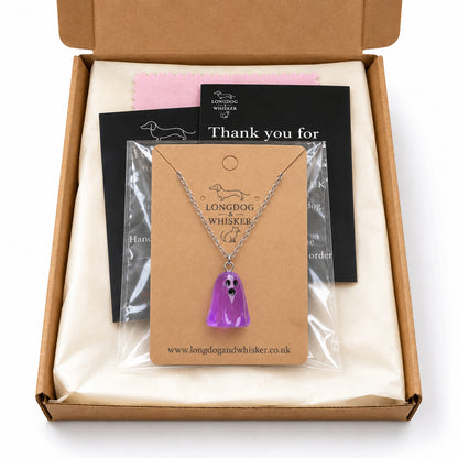 Translucent purple ghost necklace on its card in Longdog & Whisker postal packaging.