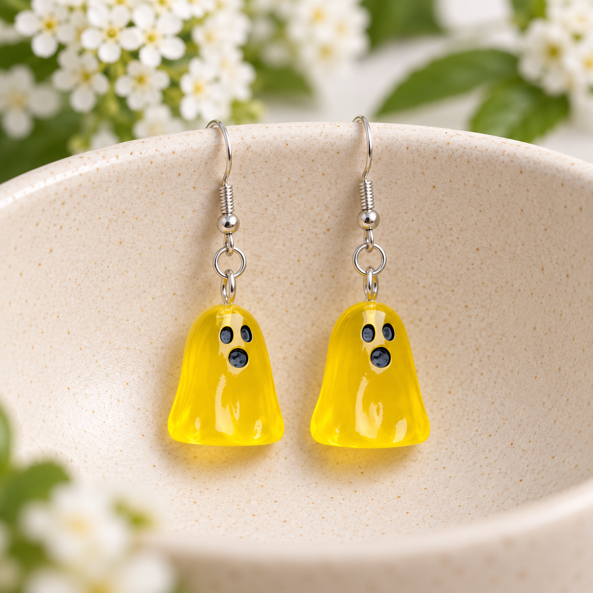 Translucent yellow ghost earrings displayed in a cream ceramic bowl