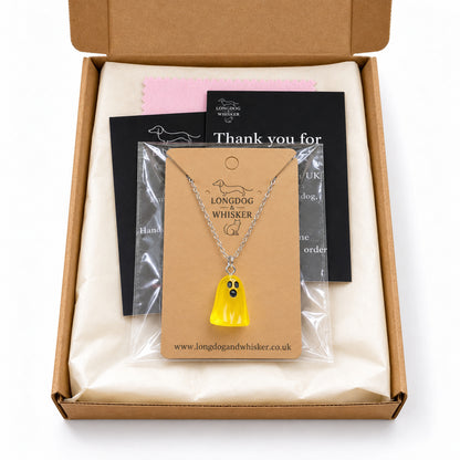 Translucent yellow ghost necklace on its card in Longdog & Whisker postal packaging.