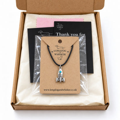 Turquoise porthole rocket necklace on its product card in gift-ready packaging