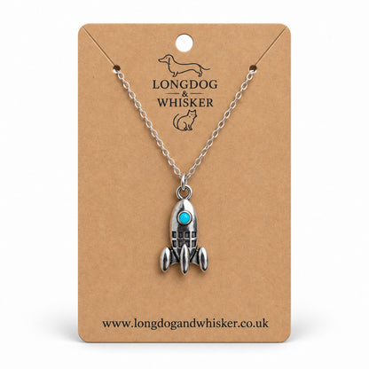 Turquoise porthole rocket necklace on a silver-tone chain, displayed on a Longdog & Whisker kraft card