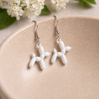 White Balloon Dog Earrings hanging from a ceramic bowl