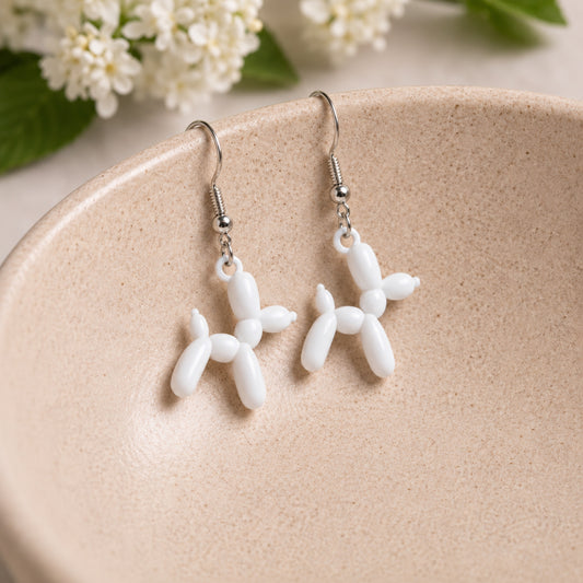White Balloon Dog Earrings hanging from a ceramic bowl