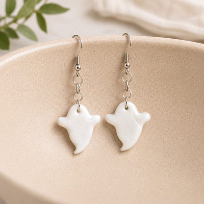 White ghost earrings hanging on a ceramic bowl
