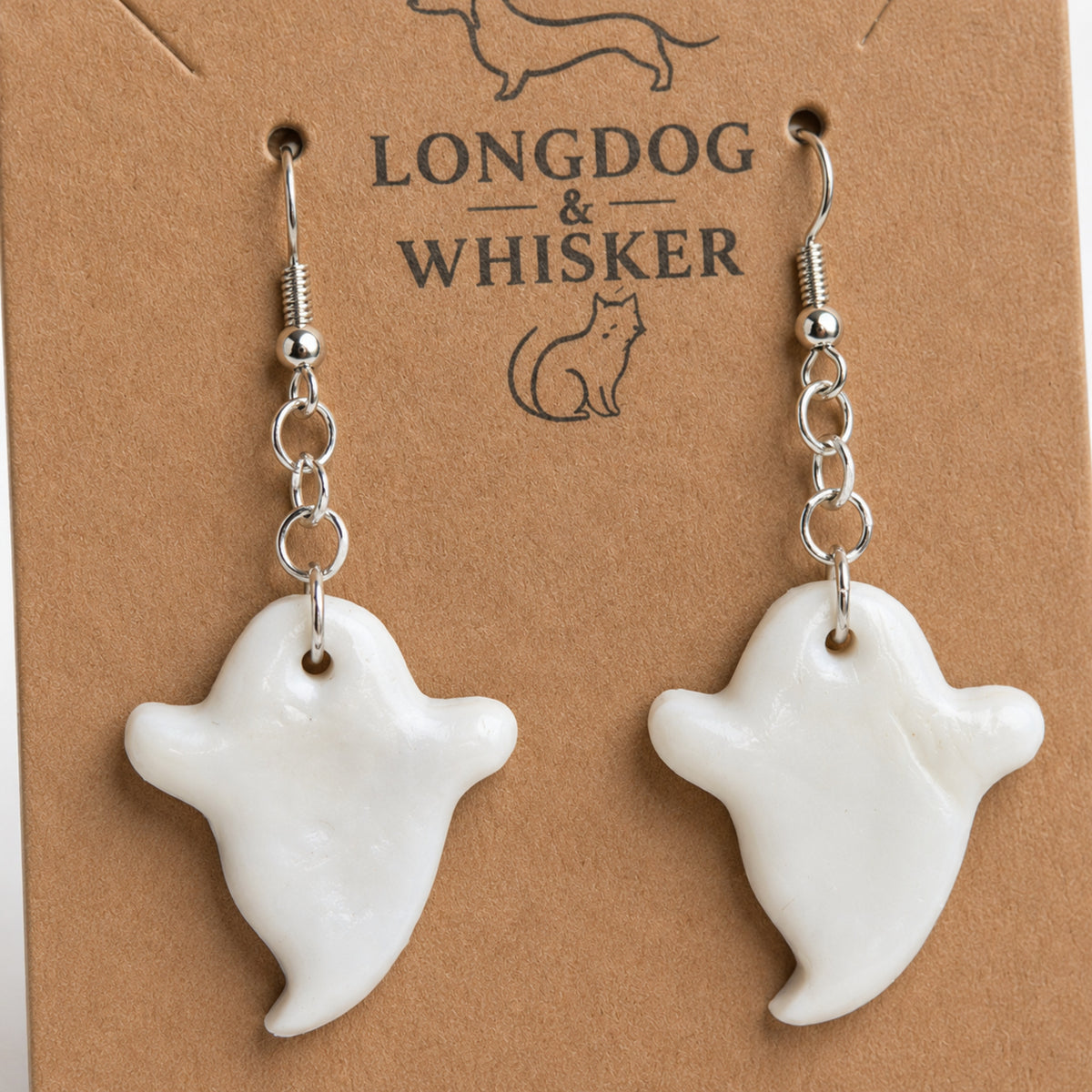 Close-up of glossy white ghost earrings and silver hooks