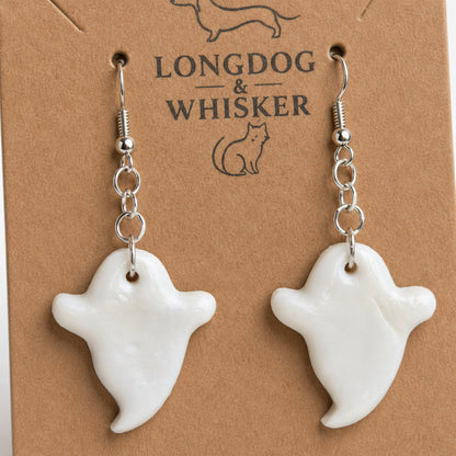 Close-up of glossy white ghost earrings and silver hooks
