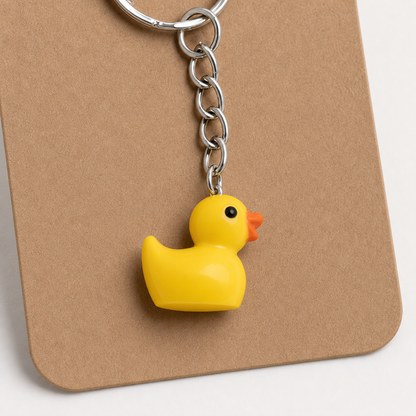 Close-up of a glossy yellow duck charm with orange beak and silver-tone chain