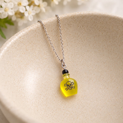 Yellow poison bottle necklace resting in a speckled ceramic bowl.