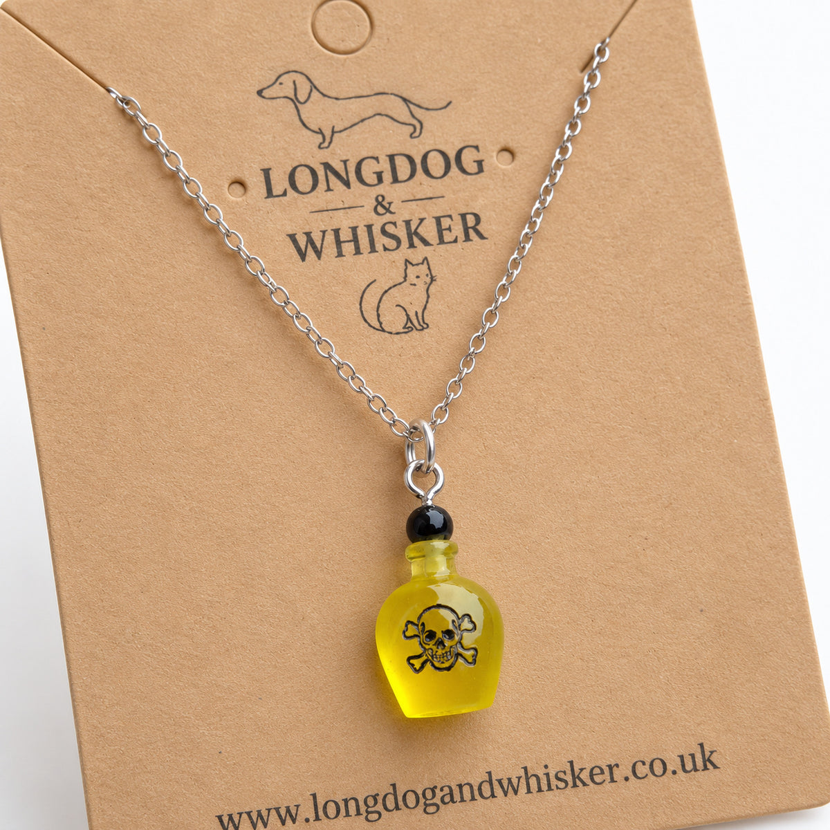 Close-up of the yellow poison bottle pendant, skull design and silver connectors.