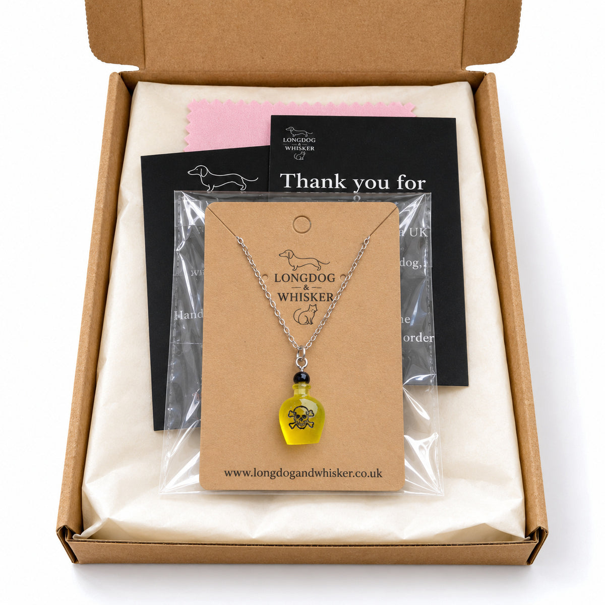 Yellow poison bottle necklace on its kraft card in Longdog & Whisker postal packaging.