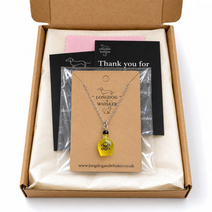 Yellow poison bottle necklace on its kraft card in Longdog & Whisker postal packaging.