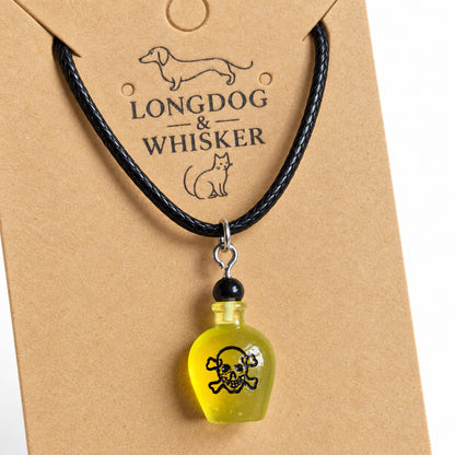 Close-up of the yellow poison bottle pendant, black skull design and silver-tone connectors on black cord.